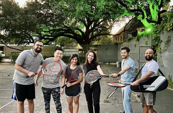 A large group of internal medicine residents pose on a tennis court