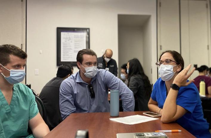 Three masked students talking together at a table