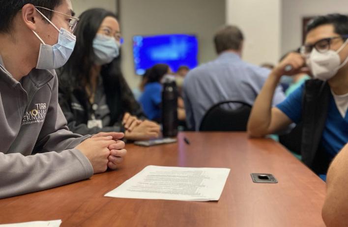 Three masked students talking together at a table