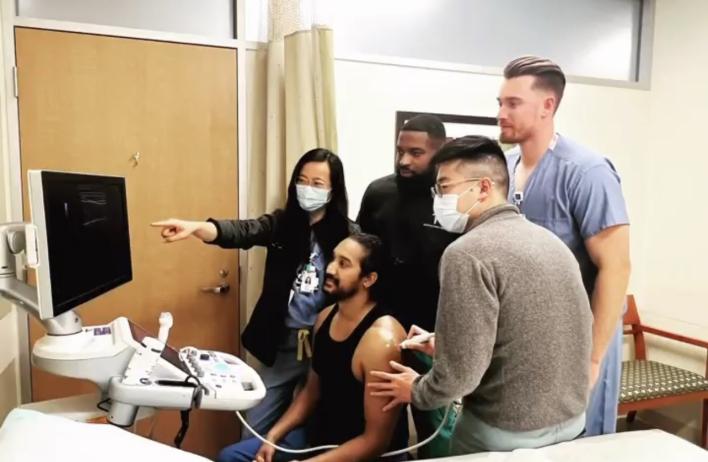 Students learning medical tools, with a sensor placed on a volunteer's arm