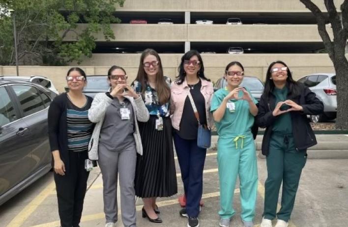 Small group of people smiling and holding up heart symbols