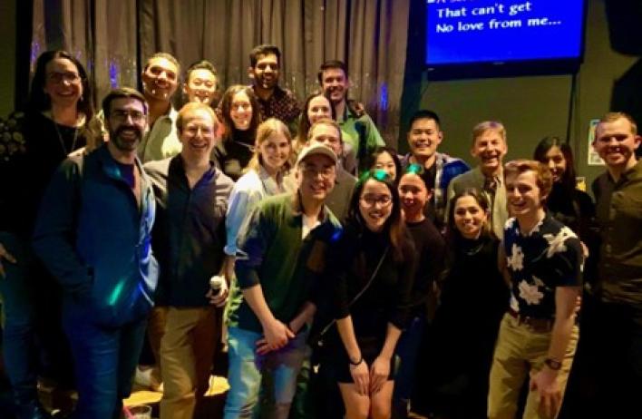 group of people smiling in front of a karaoke stage
