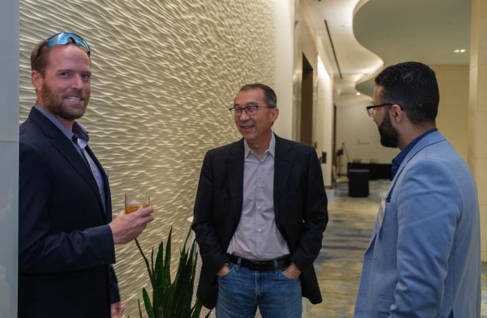 Three people smiling and laughing in a large hallway