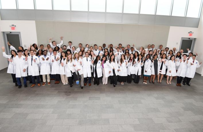 a large group of people dressed in white coats, smiling