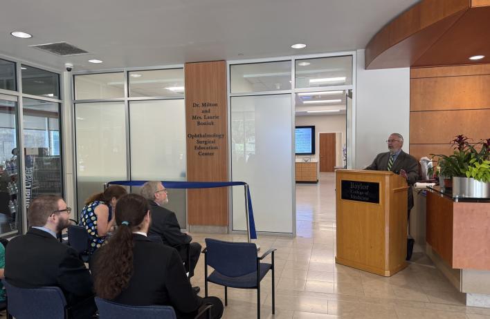 An audience watching someone speaking behind a podium.