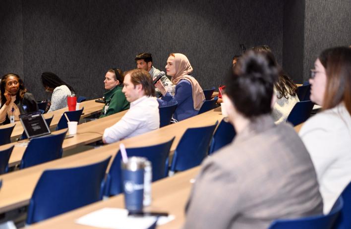 A presentation attendee holds a microphone while asking a question