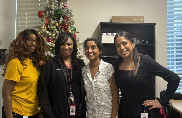 4 people standing in front of a christmas tree, smiling