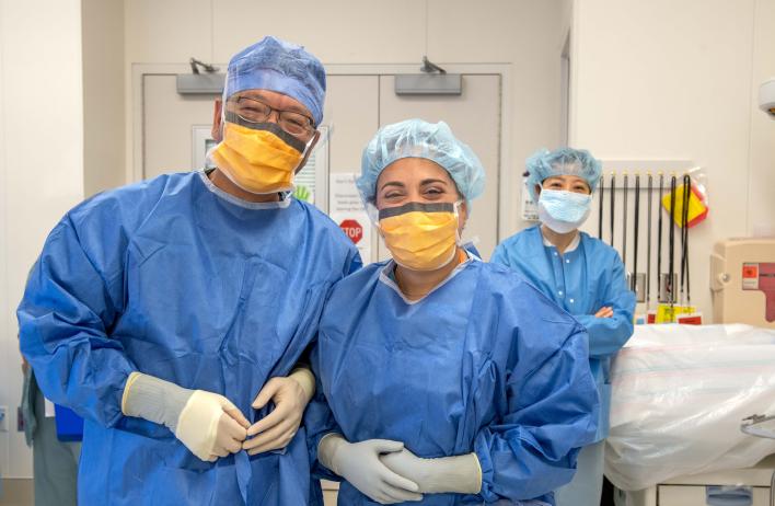 Three people wearing scrubs posing in a medical room.
