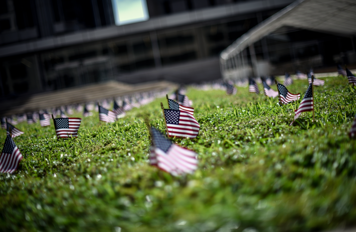 A few American flags as seen from ground level. The flags are small and planted in a green field.