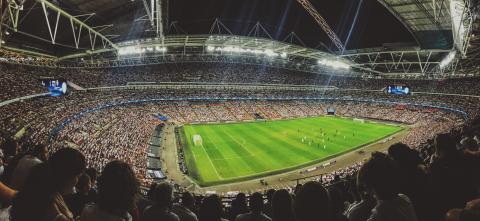 A wide shot photo of a soccer game showing the field and a full stadium