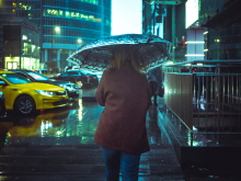 A person walking with an umbrella through a dark and rainy city street