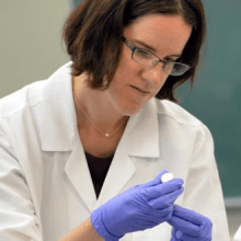 A doctor wearing gloves holding a sample