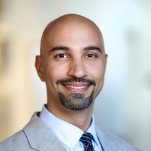man in light grey suit smiling