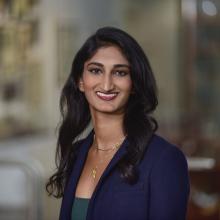 woman with dark hair in a navy suit smiling