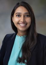 woman with dark blazer and light blue shirt smiling