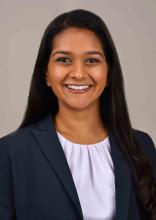 woman with long dark hair in a blazer smiling