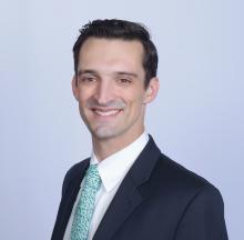 man with a light blue tie on smiling