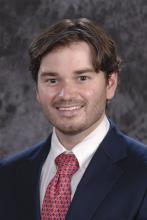 main in dark blue suit and red tie smiling