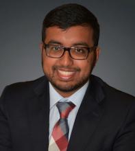 main with plaid tie and glasses smiling