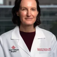 woman with short dark hair smiling and wearing a doctor coat