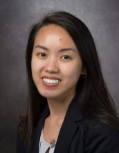 woman with long dark hair and a blazer smiling