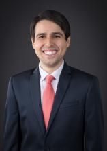 man in a dark suit and red tie smiling