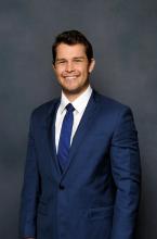 man in blue suit and white shirt smiling