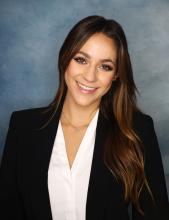woman with long brown hair and a blazer smiling