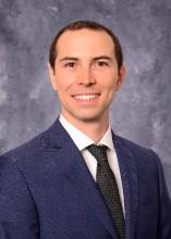 man in navy blue suit and black tie smiling