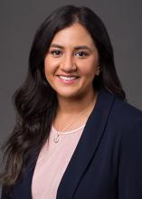 woman with long dark hair and navy blazer smiling