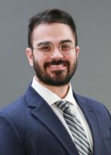 man with glasses in a suit smiling