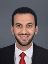 man with dark suit and red tie smiling