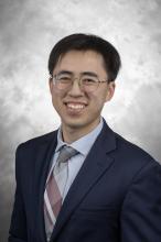 man with glasses and a blue suit smiling