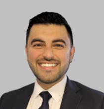 man with short black hair in a suit smiling