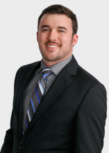 man in black blazer and striped tie smiling
