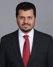 man with dark hair and red tie smiling