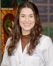 woman doctor with half up half down brown hair smiling