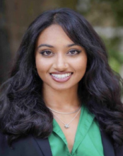 woman with long curled hair and a green top smiling