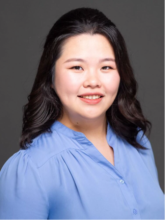 woman with dark shoulder length hair and a blue top smiling