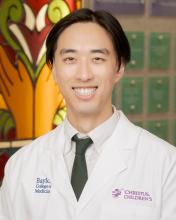 man with parted dark hair smiling