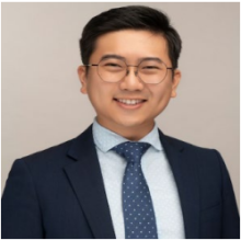 man with glasses and side parted hair smiling