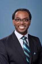 man with glasses and striped blue tie smiling