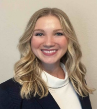 woman with faux turtle neck and curled blonde hair smiling