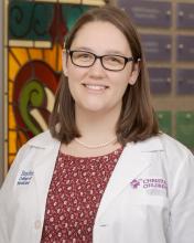 female doctor with short brown hair and glasses smiling