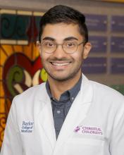 male doctor with round glasses smiling