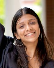 woman with dark hair and hoop earrings smiling