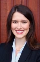 woman with long brown hair smiling with a dark blazer on