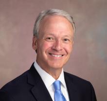 man in a suit and light blue tie smiling