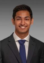 man with a navy tie on and dark hair smiling