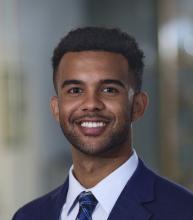 man in dark blue blazer and tie smiling